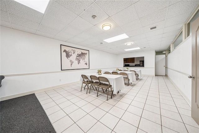 dining space with a paneled ceiling, light tile patterned flooring, and baseboards