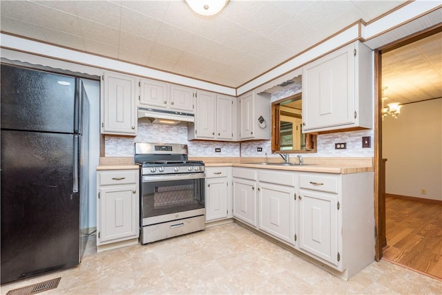 6109 Roy St, Union Twp, PA 15332 - kitchen with stainless steel gas range, freestanding refrigerator, under cabinet range hood, light countertops, and tasteful backsplash