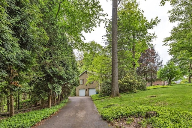 view of front of property featuring a front lawn, asphalt driveway, and an attached garage
