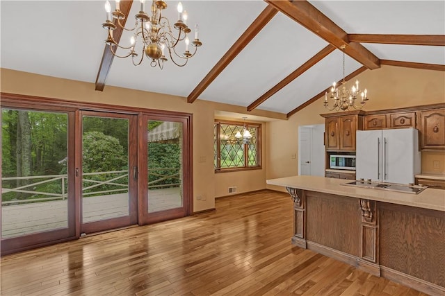kitchen featuring a chandelier, stainless steel microwave, freestanding refrigerator, and light countertops