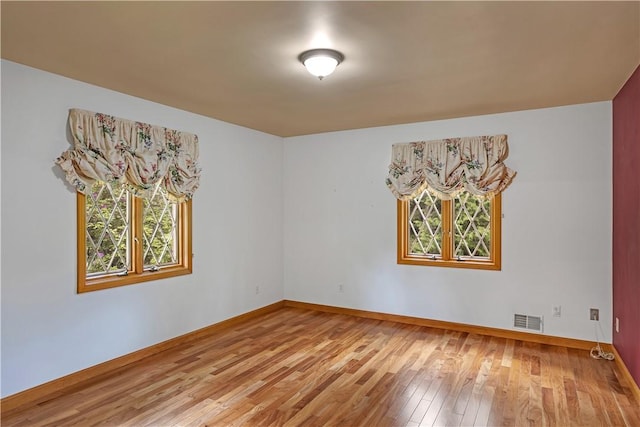 spare room with plenty of natural light, hardwood / wood-style floors, and baseboards