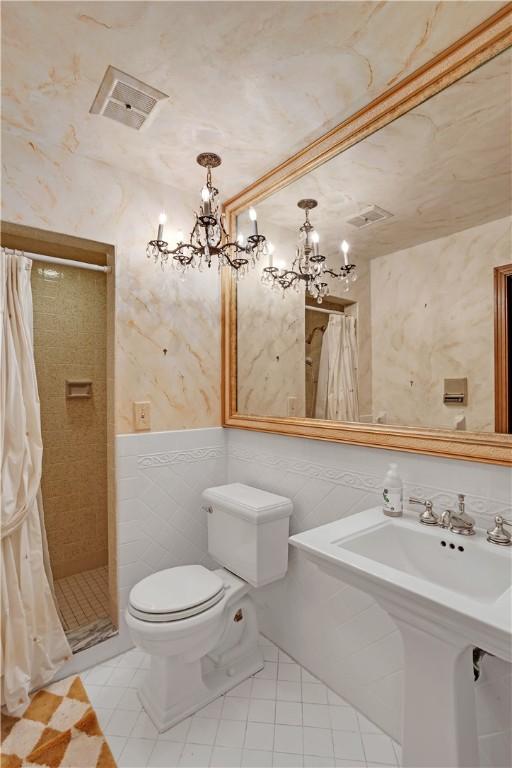 full bathroom featuring tile walls, a chandelier, tiled shower, toilet, and tile patterned floors