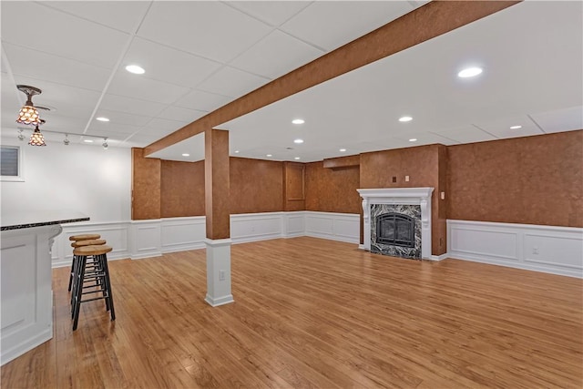 unfurnished living room with a decorative wall, light wood finished floors, a wainscoted wall, recessed lighting, and a fireplace