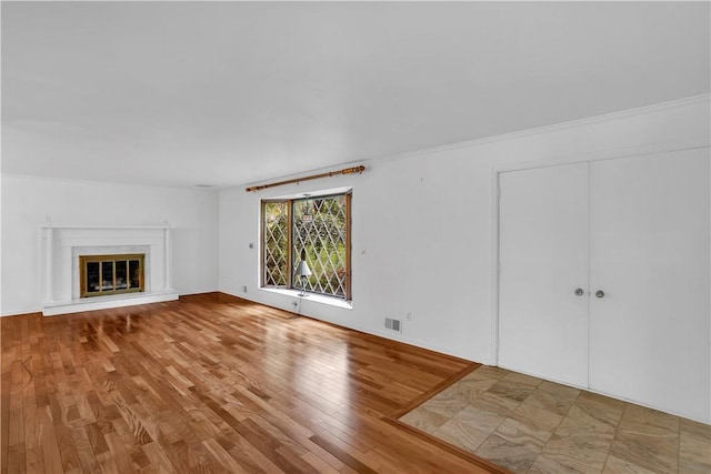 unfurnished living room featuring wood finished floors and a glass covered fireplace