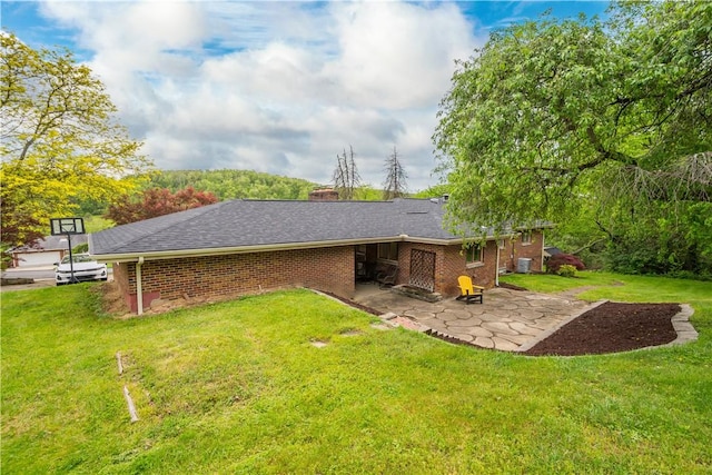 rear view of house with a patio, a lawn, brick siding, and a chimney