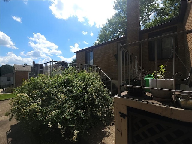 view of home's exterior featuring brick siding, a chimney, and stairway