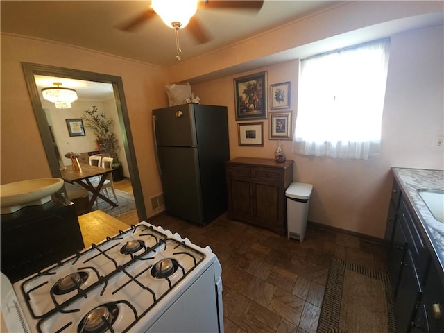 kitchen with freestanding refrigerator, white gas range oven, ceiling fan, and baseboards