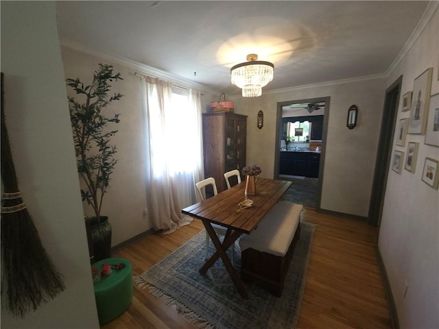 dining room featuring a chandelier, crown molding, baseboards, wood finished floors, and ceiling fan