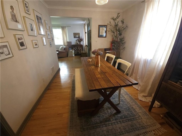 dining room with light wood finished floors, crown molding, and baseboards