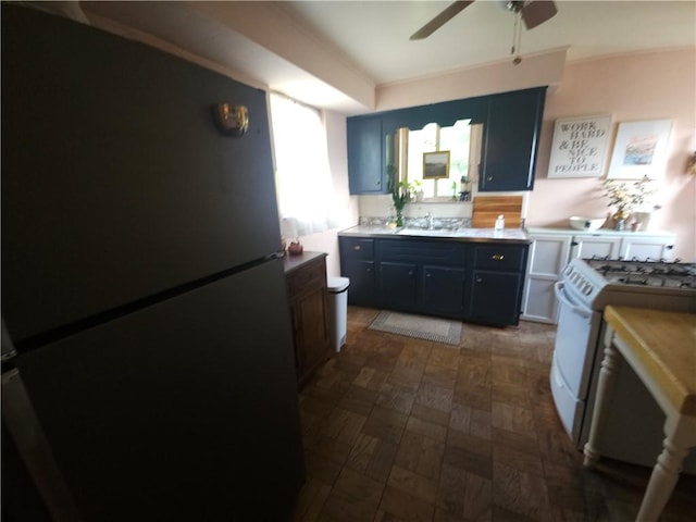 kitchen featuring freestanding refrigerator, white gas stove, a sink, ceiling fan, and light countertops