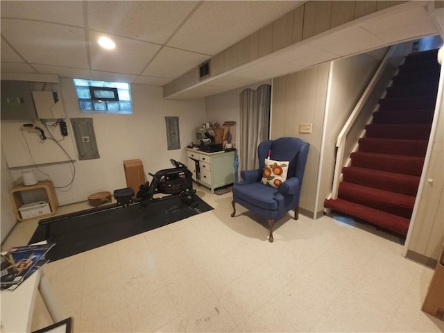 exercise room featuring a drop ceiling, electric panel, and light floors