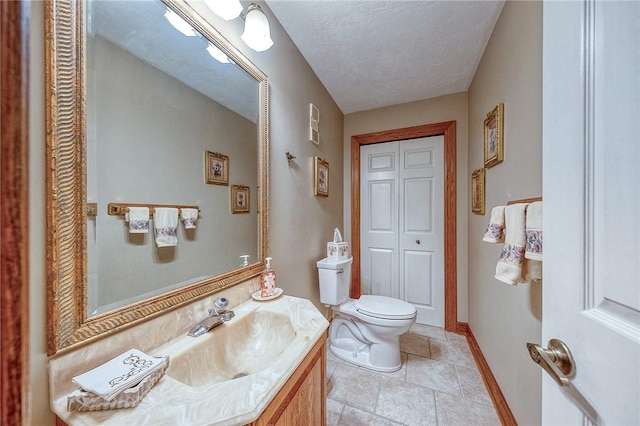 bathroom with toilet, vanity, baseboards, and a textured ceiling