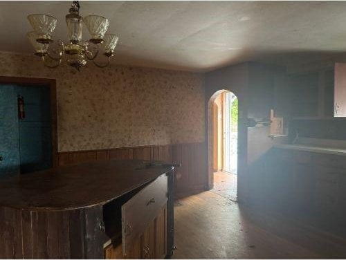 543 Highland Ave, Kittanning Boro, PA 16201 - kitchen with wainscoting, arched walkways, wallpapered walls, a chandelier, and wood finished floors