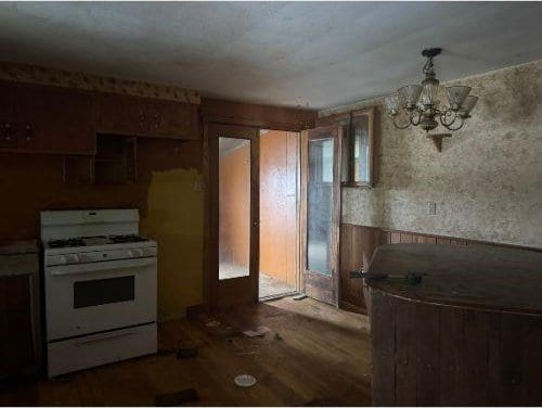 543 Highland Ave, Kittanning Boro, PA 16201 - kitchen featuring gas range gas stove, a chandelier, wood finished floors, and a wainscoted wall