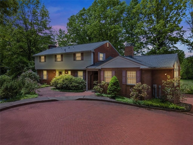 view of front of property with a chimney and brick siding