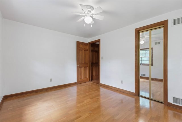 empty room featuring a ceiling fan, light wood finished floors, and baseboards