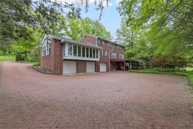 view of front of property featuring an attached garage, brick siding, and decorative driveway