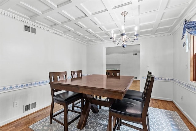 dining room with wood finished floors, a chandelier, coffered ceiling, and baseboards