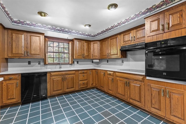 kitchen with black appliances, under cabinet range hood, brown cabinets, a sink, and dark tile patterned flooring