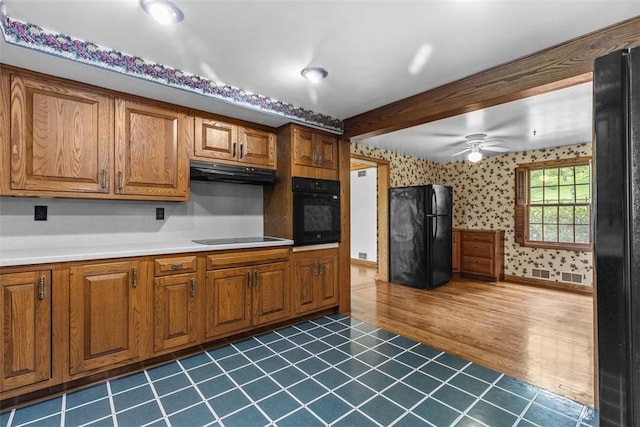 kitchen featuring black appliances, wallpapered walls, brown cabinets, ceiling fan, and under cabinet range hood