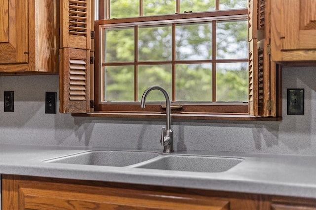 kitchen with a sink, plenty of natural light, brown cabinets, and light countertops