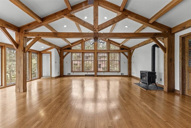 unfurnished living room with healthy amount of natural light, recessed lighting, baseboards, and a wood stove