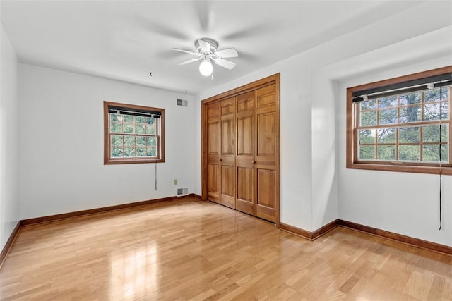 unfurnished bedroom with multiple windows, light wood finished floors, a closet, and baseboards