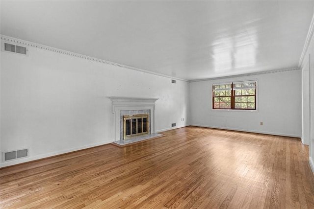 unfurnished living room with light wood-style flooring, crown molding, a premium fireplace, and baseboards