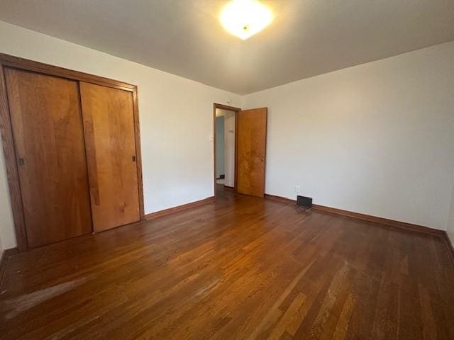 unfurnished bedroom with wood finished floors, baseboards, and a closet