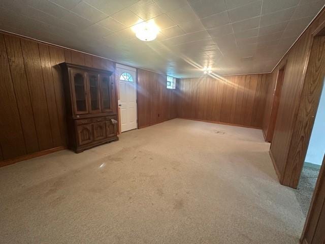 below grade area featuring wood walls and light carpet