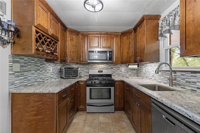 187 Anderson Rd, North Huntingdon, PA 15642 - kitchen featuring appliances with stainless steel finishes, a sink, light stone counters, decorative backsplash, and brown cabinets