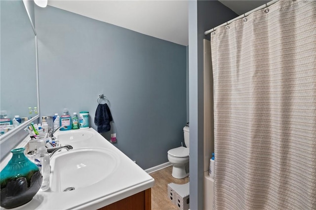 bathroom featuring toilet, curtained shower, double vanity, and wood finished floors