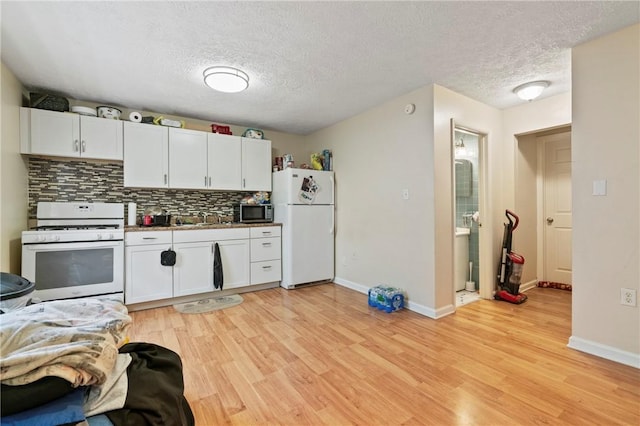 kitchen featuring white appliances, backsplash, white cabinets, light wood finished floors, and a textured ceiling