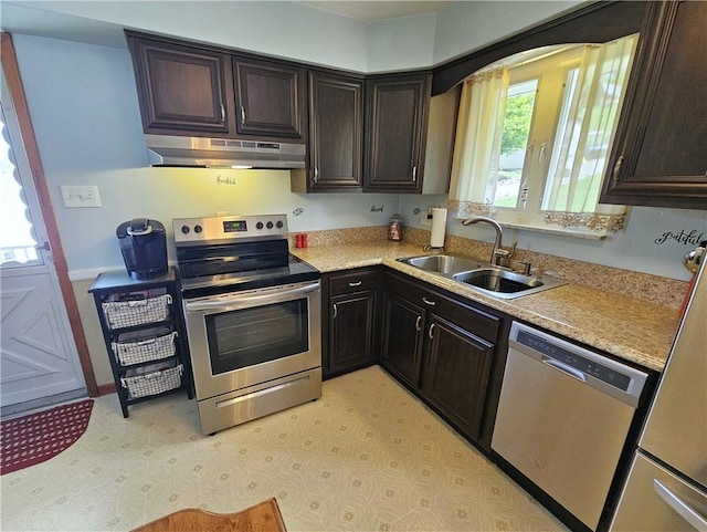 kitchen featuring stainless steel appliances, under cabinet range hood, a sink, and light countertops