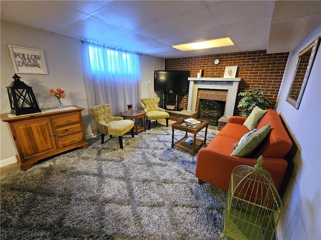 living room with baseboards, a brick fireplace, and a drop ceiling