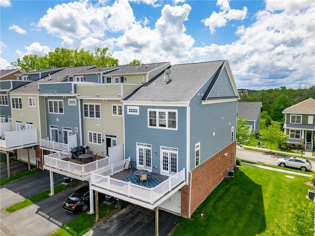 rear view of property with a wooden deck, a lawn, a residential view, and french doors