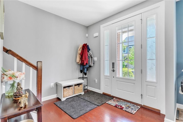 foyer with wood finished floors, baseboards, and stairs