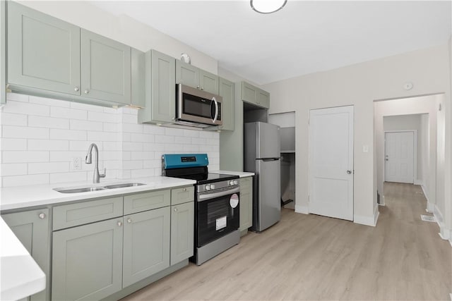 kitchen with stainless steel appliances, a sink, light wood-type flooring, and light countertops