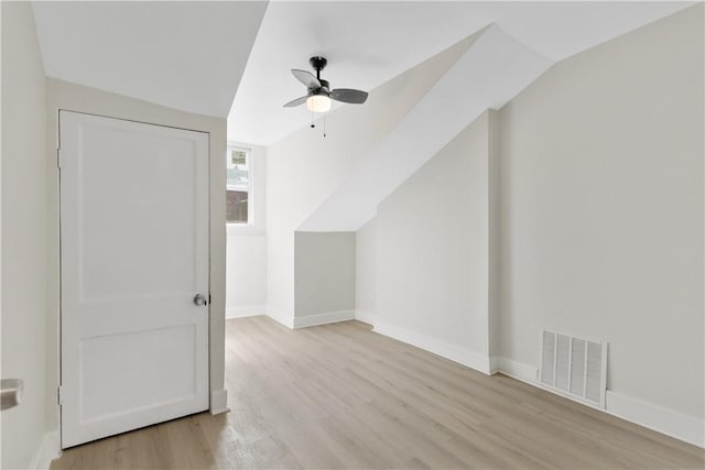 additional living space with light wood-type flooring, a ceiling fan, baseboards, and vaulted ceiling