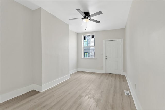 empty room featuring light wood-style floors, baseboards, and a ceiling fan