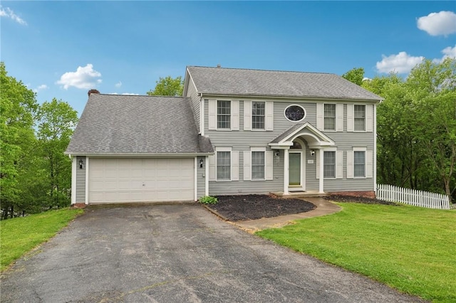 colonial-style house featuring a garage, driveway, and a shingled roof