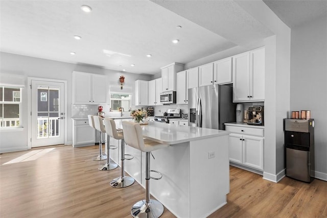 4012 Crown Dr, South Park, PA 15129 - kitchen with stainless steel appliances, a center island, light wood-style flooring, a breakfast bar area, and white cabinets