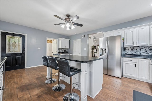 2939 Main St, Beallsville, PA 15313 - kitchen with stainless steel fridge with ice dispenser, dark countertops, wood finished floors, and white cabinetry