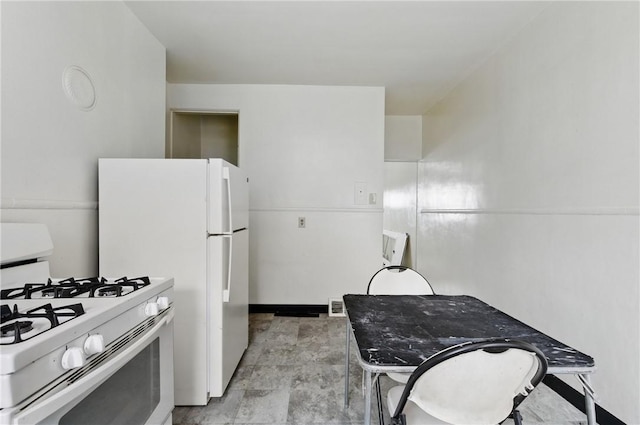 kitchen featuring white range with gas stovetop and baseboards