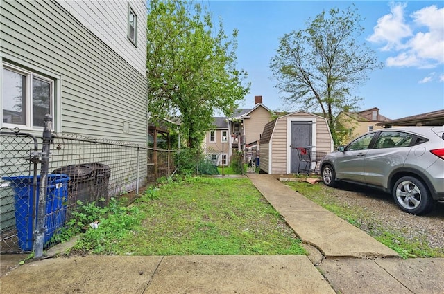 view of yard with a storage shed, fence, an outbuilding, and a residential view