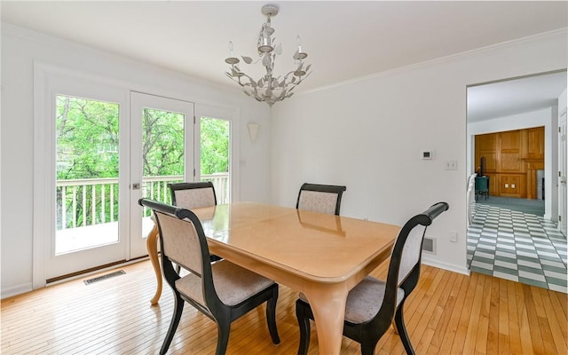 dining room featuring a chandelier, light wood-style floors, crown molding, and baseboards