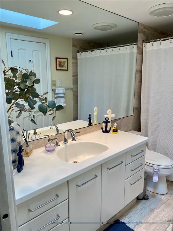 bathroom featuring vanity, toilet, a skylight, and recessed lighting