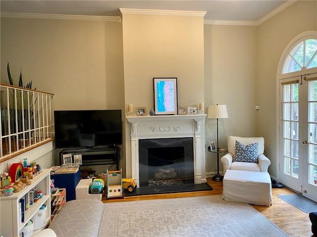 living area with wood finished floors, a glass covered fireplace, and crown molding
