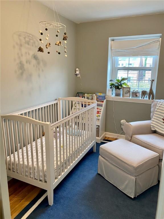 carpeted bedroom with a chandelier and a crib