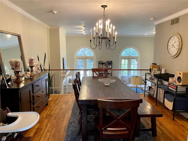 dining space with light wood finished floors, a chandelier, ornamental molding, and plenty of natural light